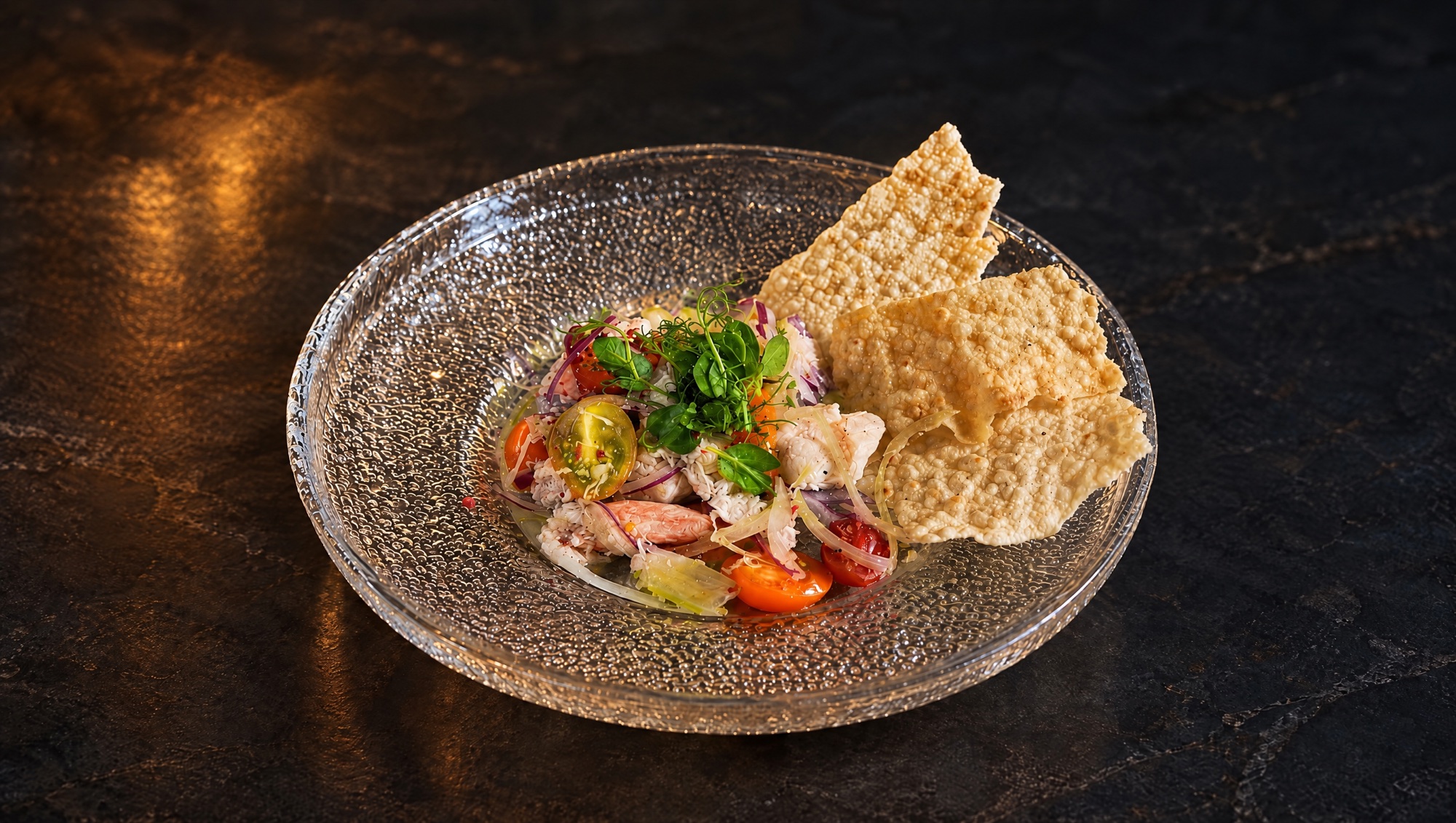 IKOS crab salad with heirloom tomato and crisp lavash in a textured glass bowl